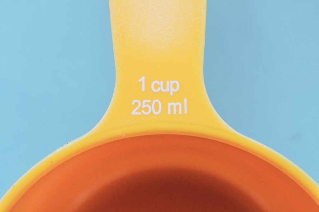 orange plastic measuring cup with yellow liquid