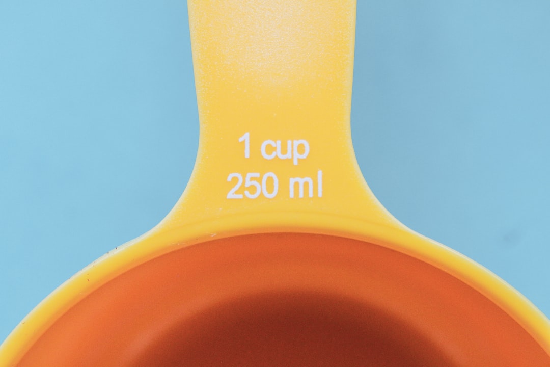orange plastic measuring cup with yellow liquid