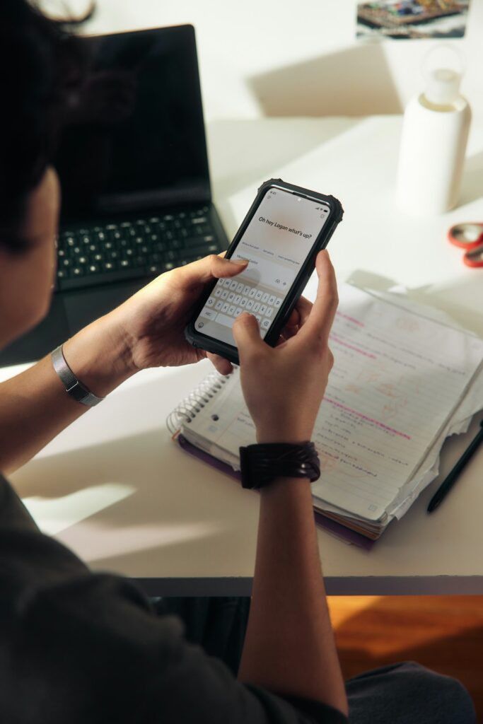 Person using a smartphone over a notebook