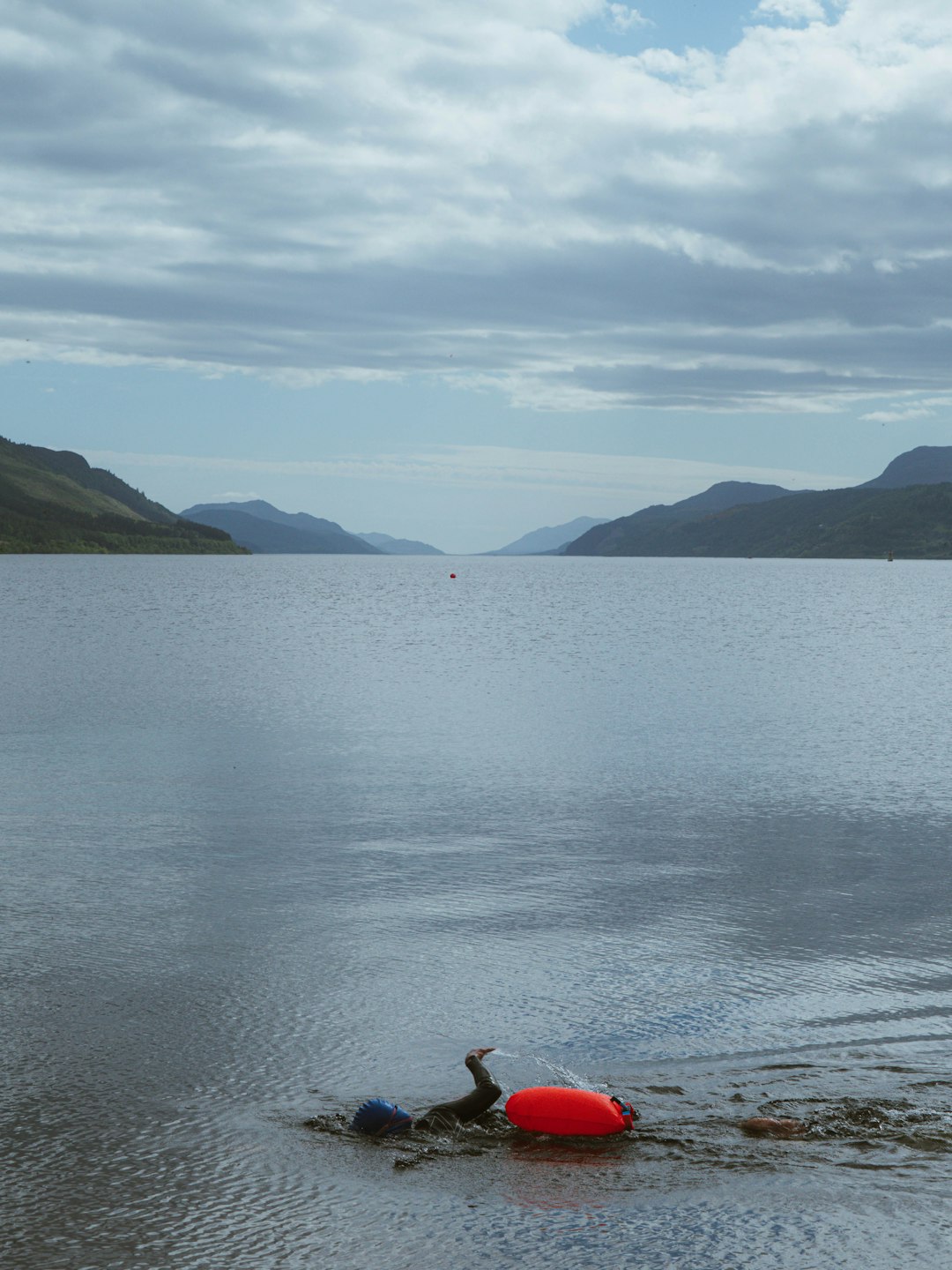 Red buoy on a calm loch with distant mountains